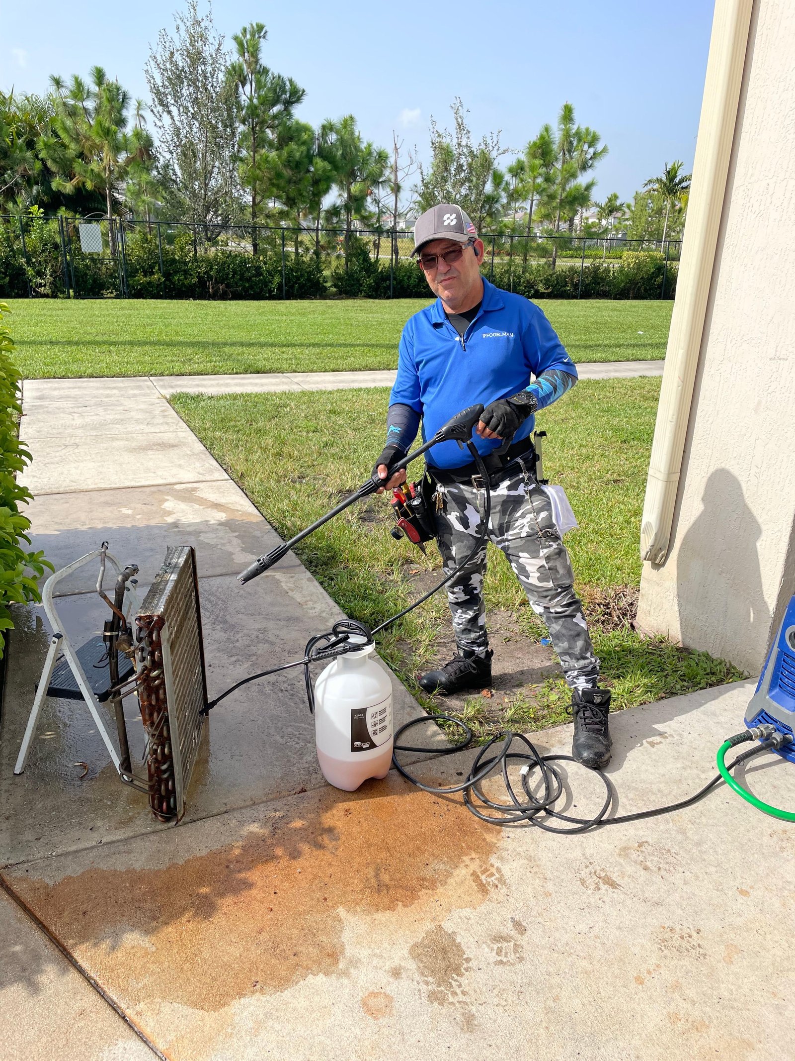 Technician pressure washing HVAC equipment